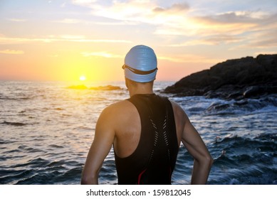 young athlete triathlon in front of a sunrise over the sea