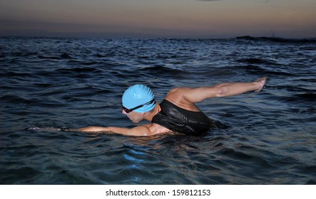 young athlete triathlon swimming in the sea while dawns