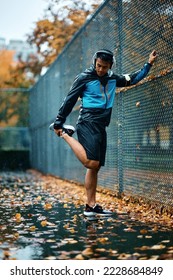 Young athlete warming up while exercising in the park during rainy day. Copy space.
