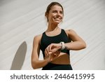 Young athlete woman looking at smartwatch and counting calories burned. Healthy life concept 