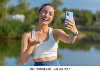 Young athlete woman talking on video call in urban city park. waving and look at smartphone camera happy girl shares updates on her training and upcoming competitions Enthusiasm and energy outdoors. - Powered by Shutterstock