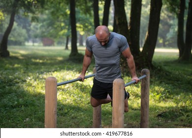 Young Athlete Working Out Triceps In An Outdoor Gym - Doing Street Workout Exercises