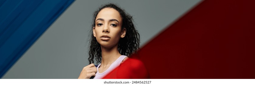 A young, athletic African American woman stands in a studio with colorful glass panels, her gaze intense and focused. - Powered by Shutterstock