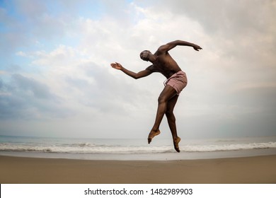 young athletic and attractive black African American man dancing contemporary ballet in graceful and dramatic artistic performance at beautiful beach jumping high on air above the sea - Powered by Shutterstock