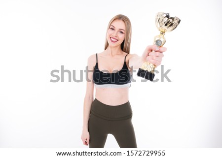 Young athletic beautiful girl with winning cup in hands on white background, woman with champion cup