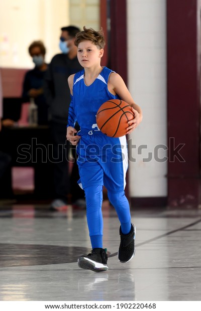 Young\
athletic boy playing in a game of\
basketball