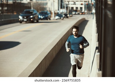 Young and athletic caucasian man jogging on a bridge in the city - Shutterstock ID 2369751835