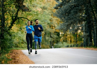 Young athletic couple jogging on the road while working out outdoors. Copy space.  - Powered by Shutterstock