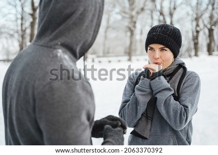 Young athletic couple talking in a snowy city park after winter jogging workout