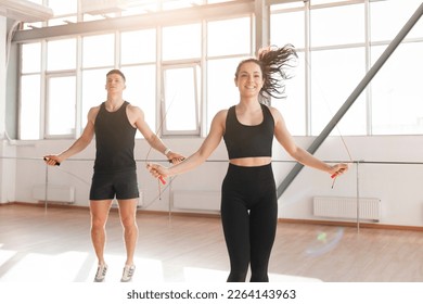 young athletic couple in training jump rope in the gym in the morning, man coach and woman go in for sports, healthy lifestyle - Powered by Shutterstock