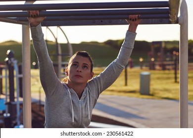 young athletic fitness woman working out at outdoor gym doing pull ups at sunrise - Powered by Shutterstock