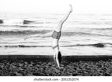 Young Athletic Girl During A Calisthenics With Legs Up On The Shore Of The Beach