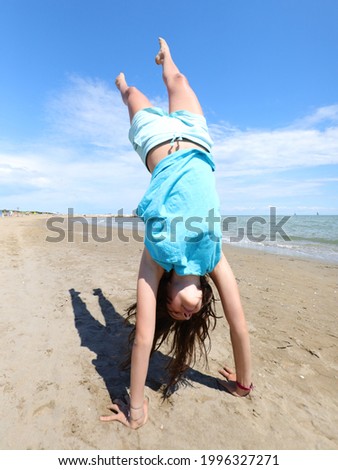Young athletic girl while doing a pirouette with legs in the air by the sea