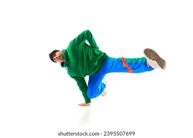 Young athletic man, b-boy dancing hip-hop, breakdance on one hand raising legs up in motion against white background. Concept of action, art, beauty, sport, youth. Dancer shows breakdance figures - Powered by Shutterstock