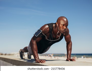 Young athletic man doing push-ups. Fitness model doing outdoor workout. Muscular and strong guy exercising. 