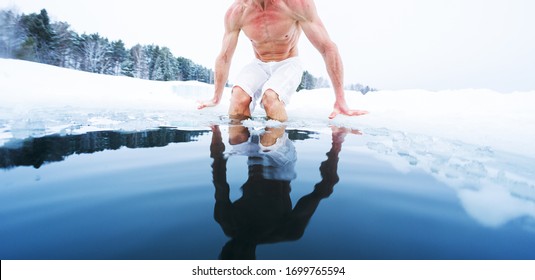 Young athletic man going to have ice bath in the winter pond