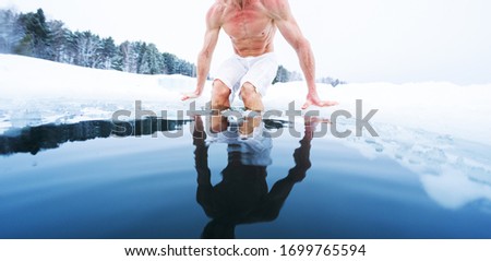 Young athletic man going to have ice bath in the winter pond