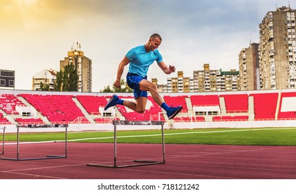 Young Athletic Man Jumping Over Hurdles 