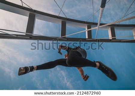 Young athletic man jumping while exercising on city bridge at the morning. Young fit man doing sports and recreation outdoors. Sport and recreation outside in city. Staying fit and doing exercises. 