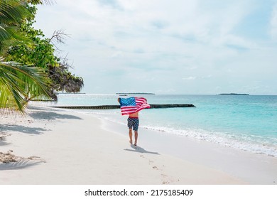 young athletic man stands in swimming trunks with an American flag on his shoulders near ocean sea shore, concept of celebrating America's USA Independence Day on July 4 and patriotic education, sense - Powered by Shutterstock