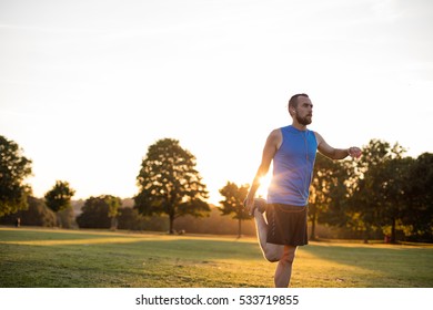 Young Athletic Man Stretching At Sunset In The Park