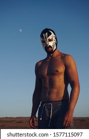 Young Athletic Man With A Strong Body In A Luchador Mask Standing In A Sunset Light.