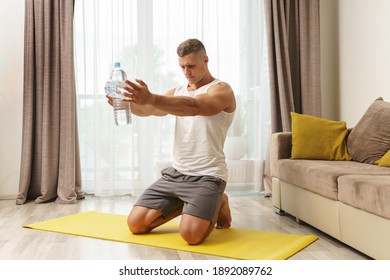 Young athletic man using bottles of water like an alternative of dumbbells for home workout