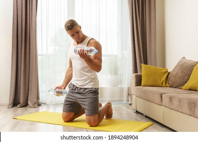 Young athletic man using bottles of water like an alternative of dumbbells for home workout - Powered by Shutterstock