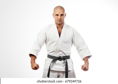 Young athletic man in white kimono for sambo, judo, jujitsu posing on white background, looking straight, position of fighting post, hands clasped in fist - Powered by Shutterstock