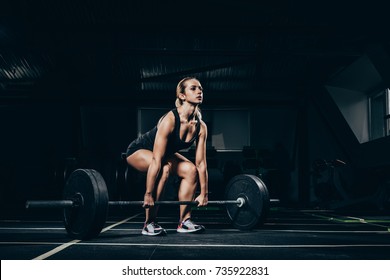 Young athletic sportswoman squatting while lifting a barbell with weights in gym - Powered by Shutterstock