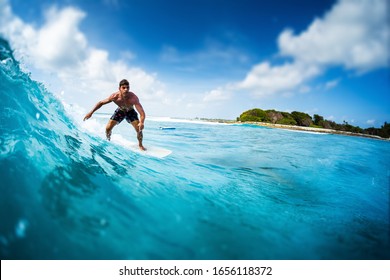 Young athletic surfer rides the ocean wave on Sultans surf spot in Maldives. Tilt shift effect applied