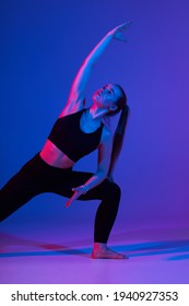 Young athletic woman is doing sport. Studio shot, colored gel filters - Shutterstock ID 1940927353