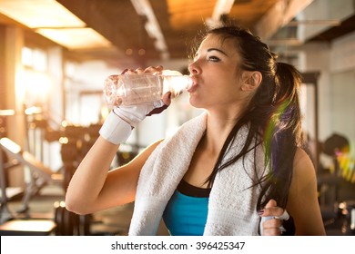 Young Athletic Woman Drinking Water In Gym.