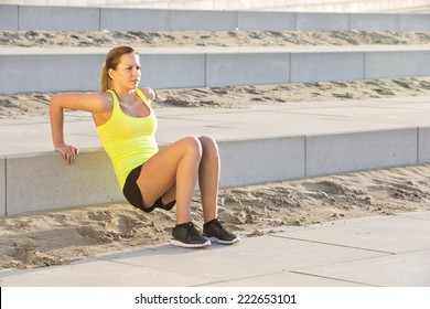 Young, athletic woman excercising her upper body during a bootcamp training session on a beach boulevard - Powered by Shutterstock