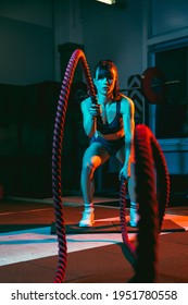 Young Athletic Woman, Fitness Instructor Training In Gym In Mixed Neon Light.