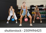 Young athletic woman lifting heavy kettlebell in gym