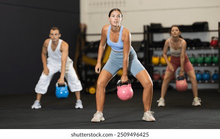 Young athletic woman lifting heavy kettlebell in gym