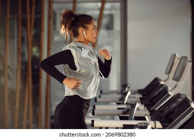 Young athletic woman listening music over earphones while running on treadmill at gym. - Powered by Shutterstock