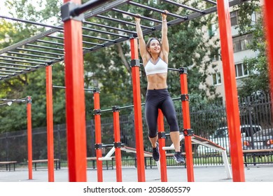 Young Athletic Woman Moves On Her Arms Along A Horizontal Ladder To The Workout Ground