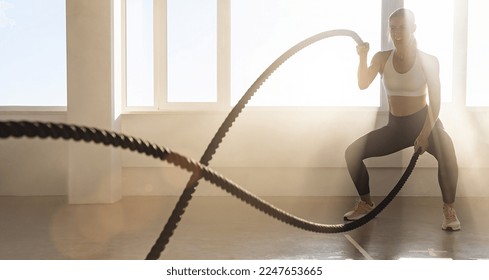 Young athletic woman with perfect body doing crossfit exercises with a rope in the gym. - Powered by Shutterstock