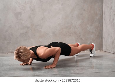 Young athletic woman performs push-up exercise. Female trainer doing sports exercises motivating to do sports, promoting a healthy lifestyle. - Powered by Shutterstock