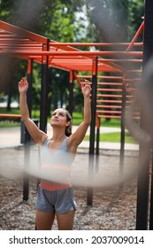 Young Athletic Woman With Raised Hands Preparing For Exercise On Pull Up Bar In Outdoor Gym