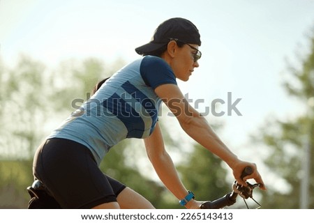 Young athletic woman riding a bike in the park on a summer day