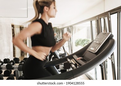 Young Athletic Woman Running On Treadmill During Fitness Workout. Long Exposure For Motion Blur.