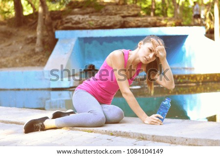 Young athletic woman is tired she sits on the concrete she's got a headache
