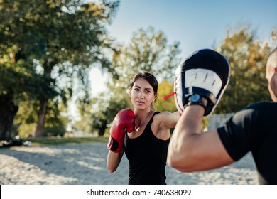 A young athletic woman training boxing with her fitness trainer. - Powered by Shutterstock