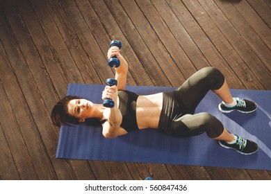 Young Athletic Woman Training Hard With Dumbells At Home, Lying At Mat. Upper View