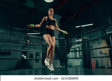 Young athletic woman training with jumping rope on boxing ring wearing fighting bandages - Powered by Shutterstock