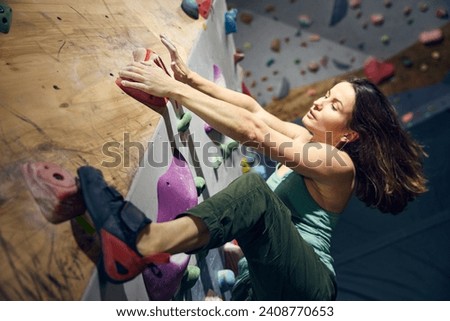 Young athletic woman, training, practicing bouldering activity indoors, climbing wall. Concept of sport, bouldering, sport climbing, hobby and active lifestyle, training course