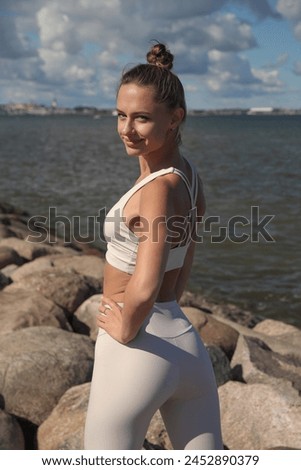 young athletic woman in a white tracksuit by the sea